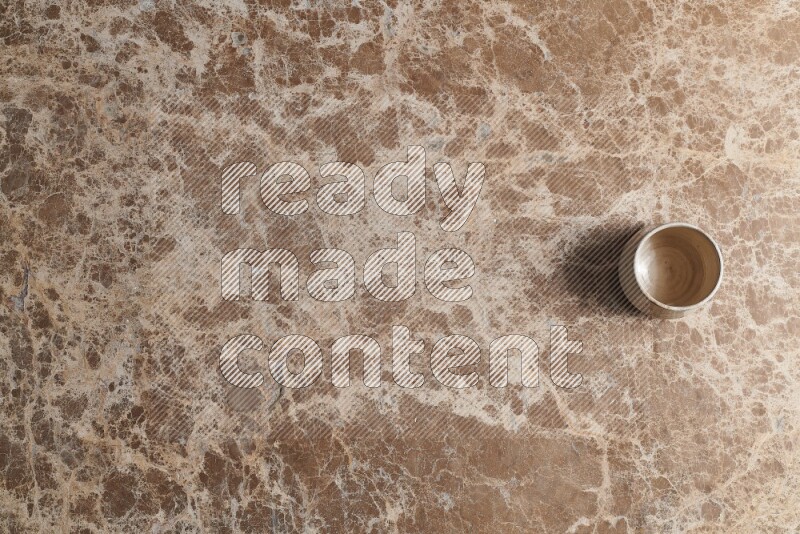 A multicolored pottery bowl on beige marble background