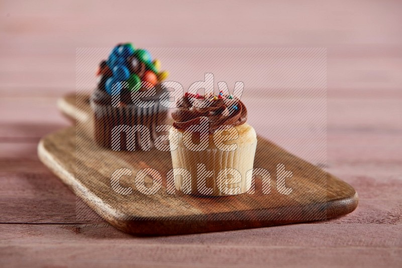 Vanilla mini cupcake topped with chocolate cream on a wooden board