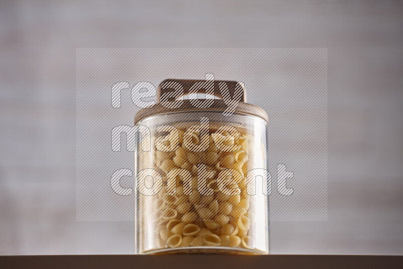 Raw pasta in glass jars on beige background