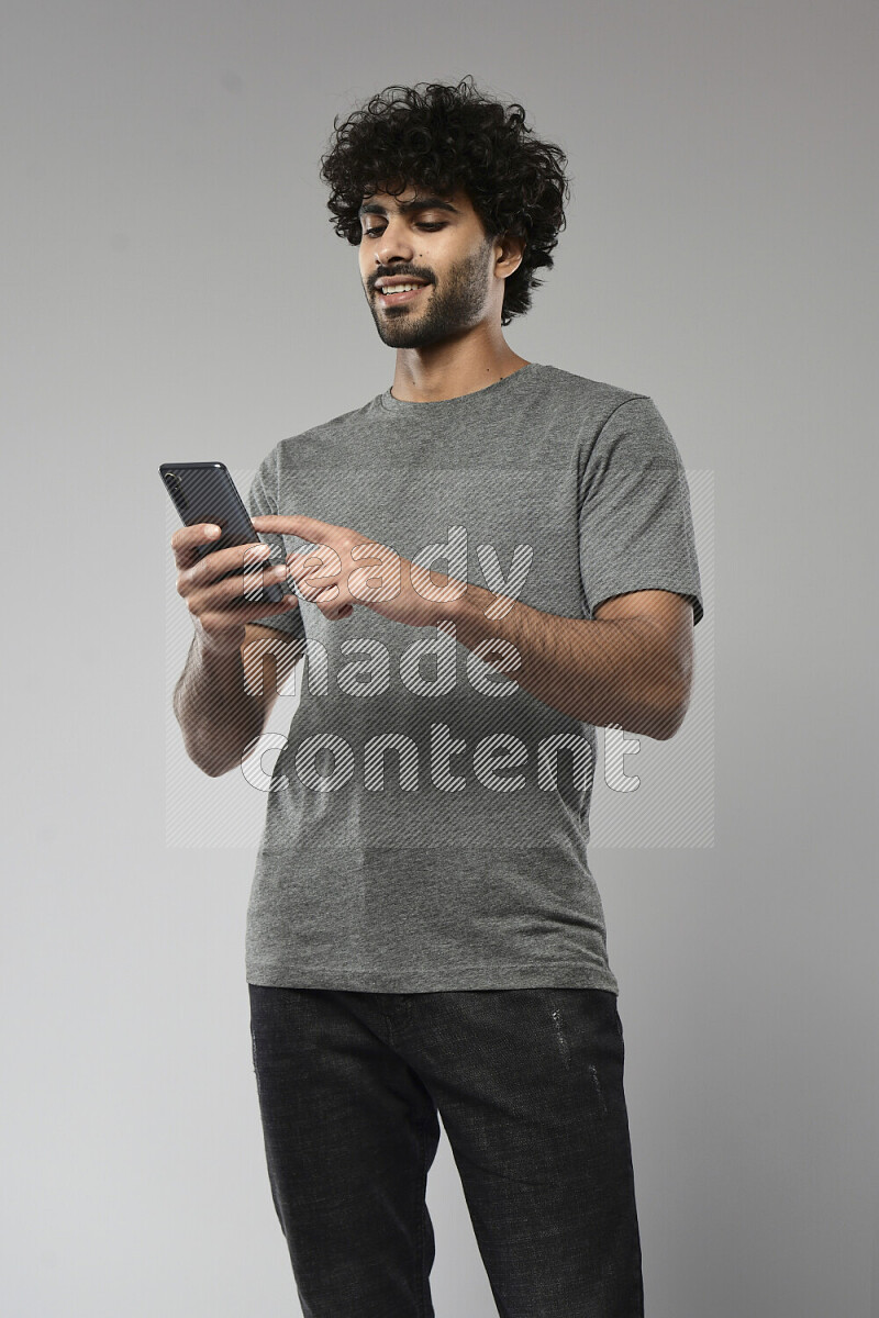 A man wearing casual standing and browsing on the phone on white background