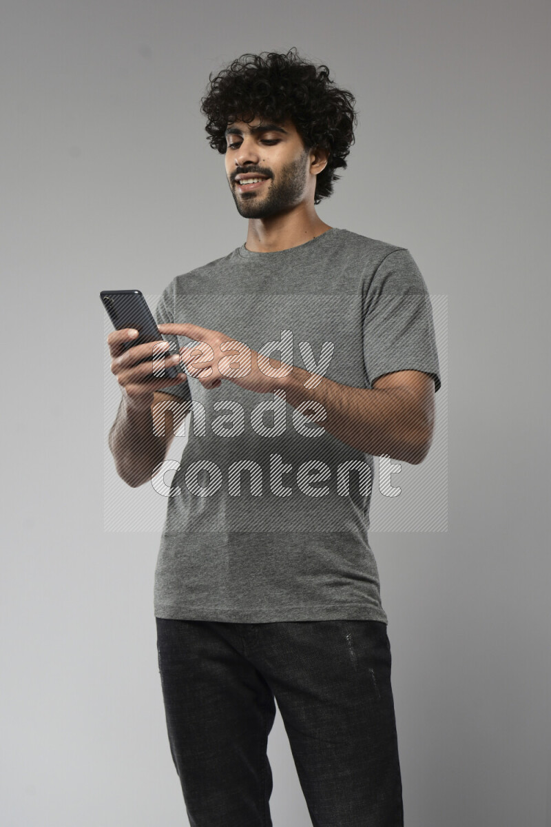 A man wearing casual standing and browsing on the phone on white background