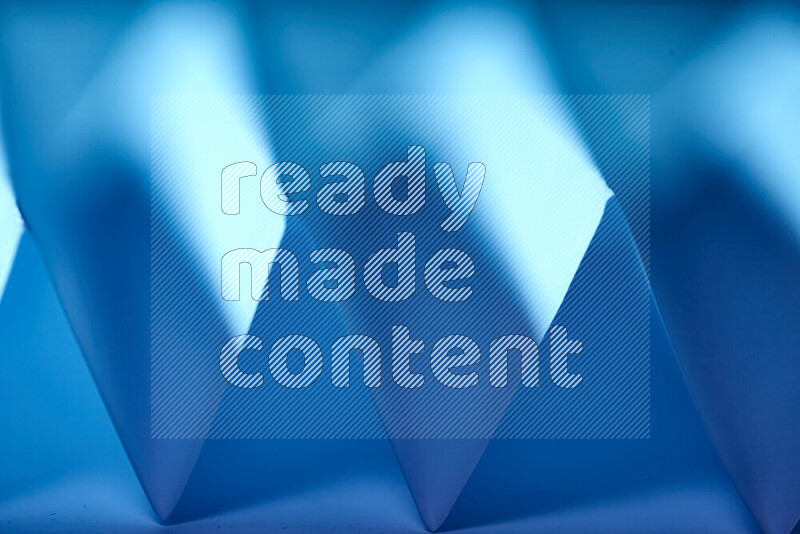 A close-up abstract image showing sharp geometric paper folds in blue gradients