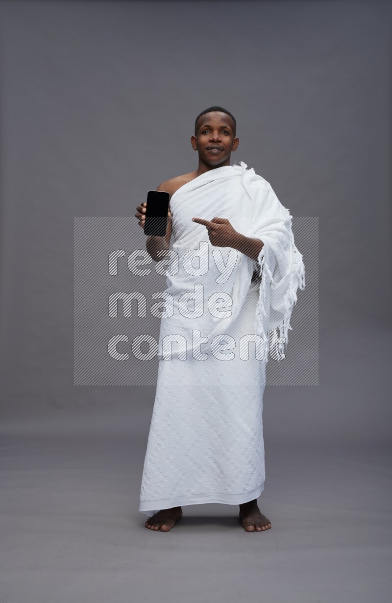 A man wearing Ehram Standing showing phone to camera on gray background