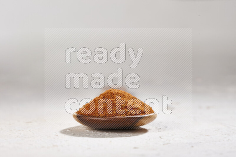 A wooden ladle full of ground paprika powder on white background