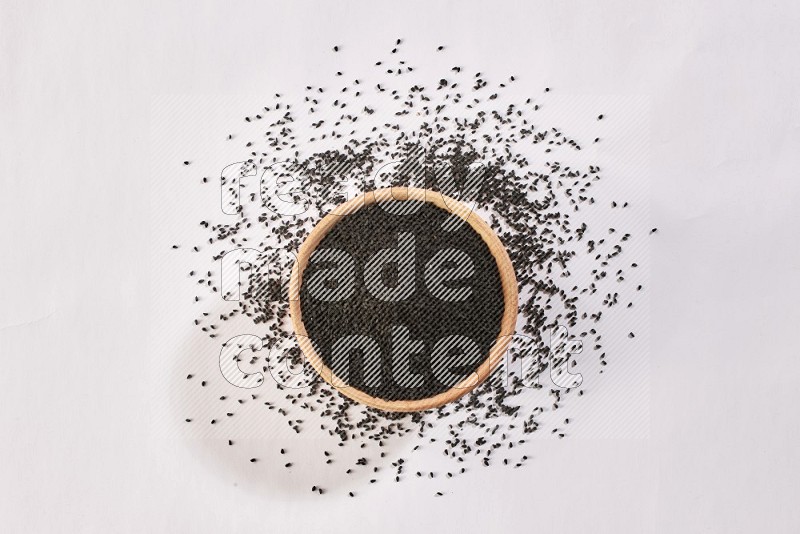A wooden bowl full of black seeds and more seeds spread on a white flooring in different angles