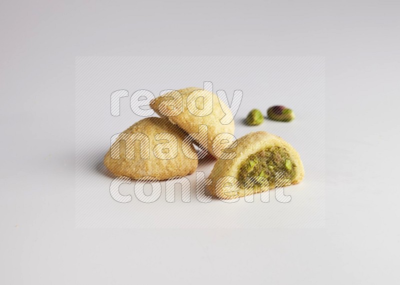 Three Pieces of Maamoul filled with pistachio paste  one of them is cut direct on white background