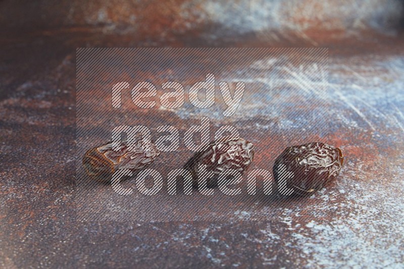 three madjoul dates on a rustic reddish background