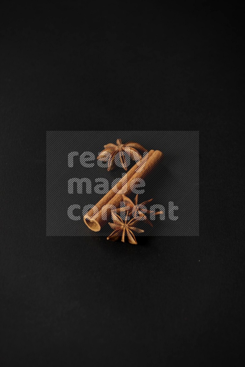 Star Anise herb and a cinnamon stick on a black background