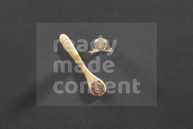 وعاء خشبي ممتلئ بحبوب بذر الكتان مع زجاجة من زيت بذر الكتان علي خلفية سوداء