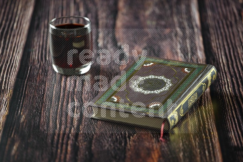 Quran with dates, prayer beads and different drinks all placed on wooden background