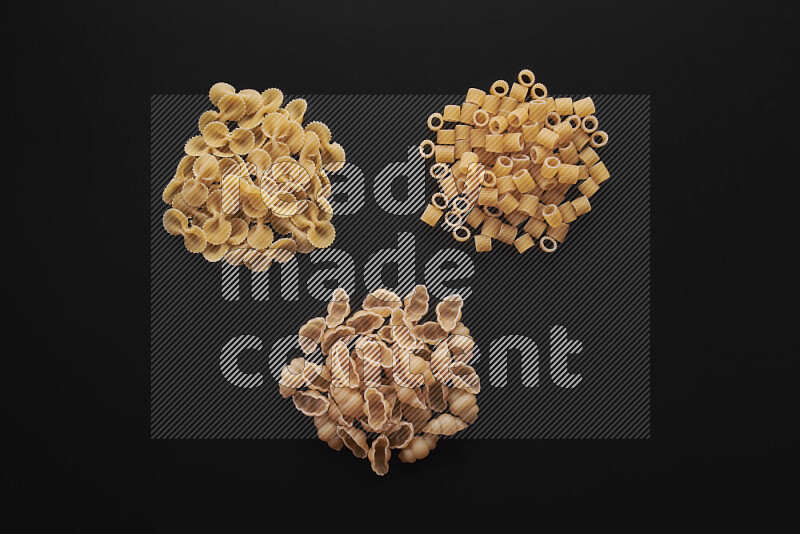 Different pasta types in bunches on black background