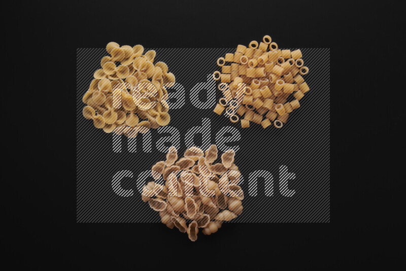 Different pasta types in bunches on black background