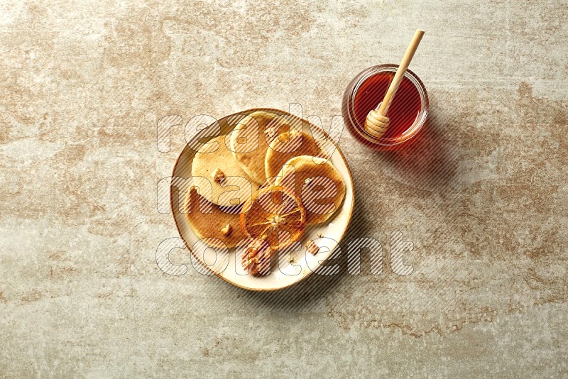 Five stacked dried orange mini pancakes in an irregular plate on beige background