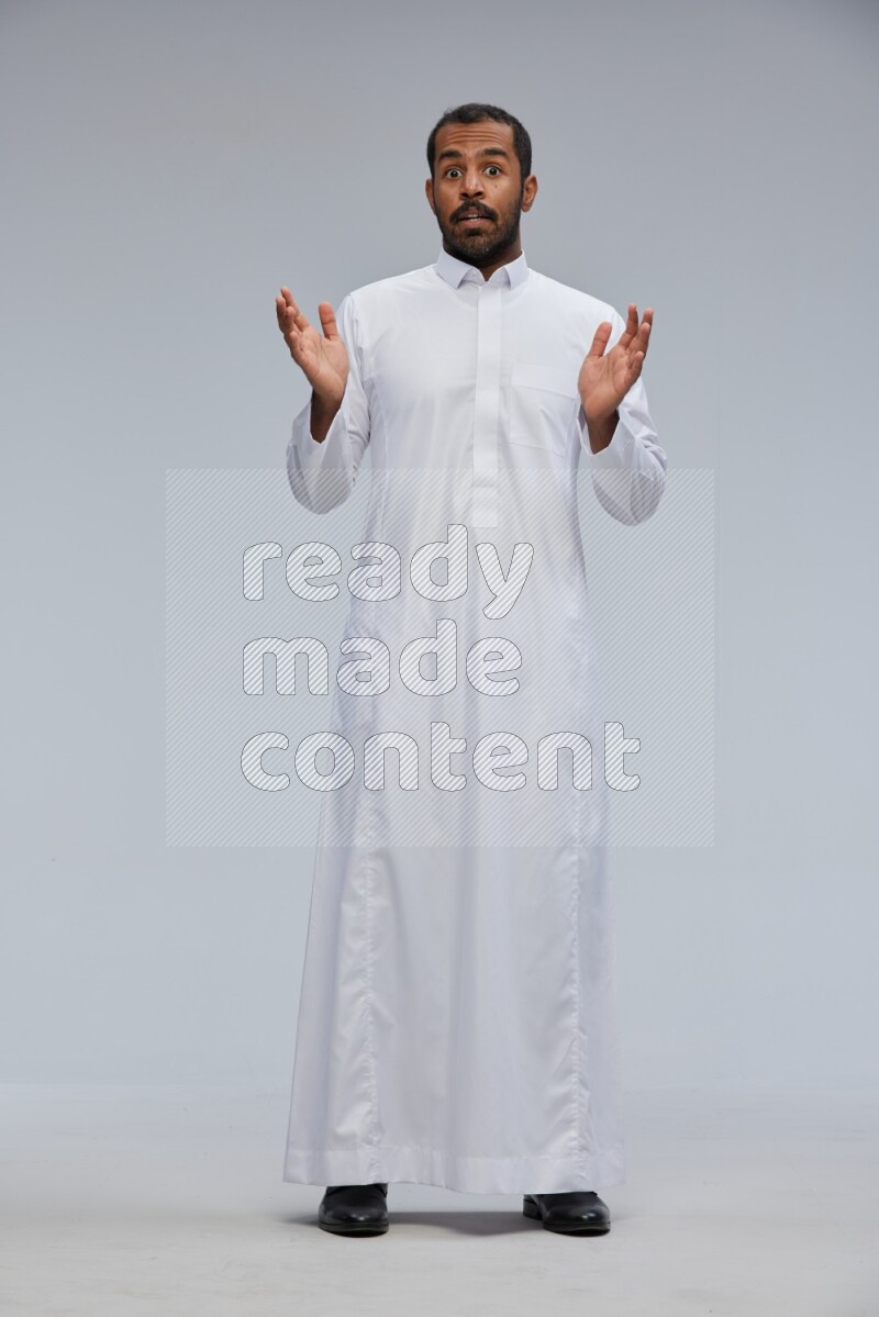 Saudi man Wearing Thob standing interacting with the camera on Gray background