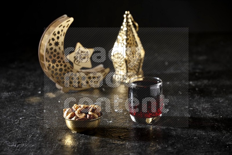 Nuts in a metal bowl with Hibiscus beside golden lanterns in a dark setup