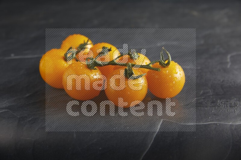 Yellow cherry tomato vein on a textured black slate background 45 degree