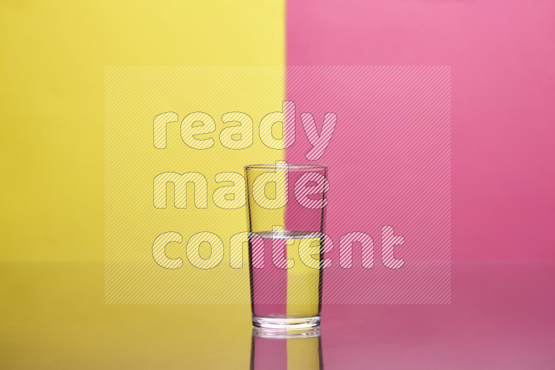 The image features a clear glassware filled with water, set against yellow and pink background
