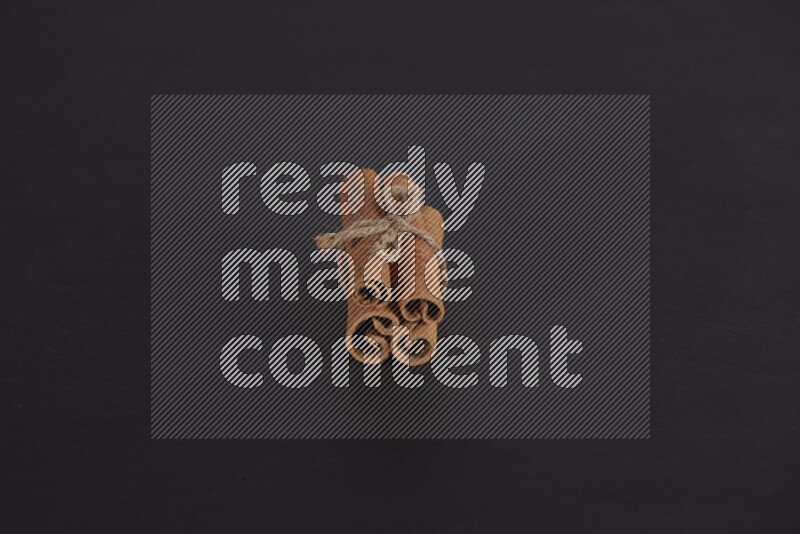 4 Cinnamon sticks stacked and bounded on black flooring