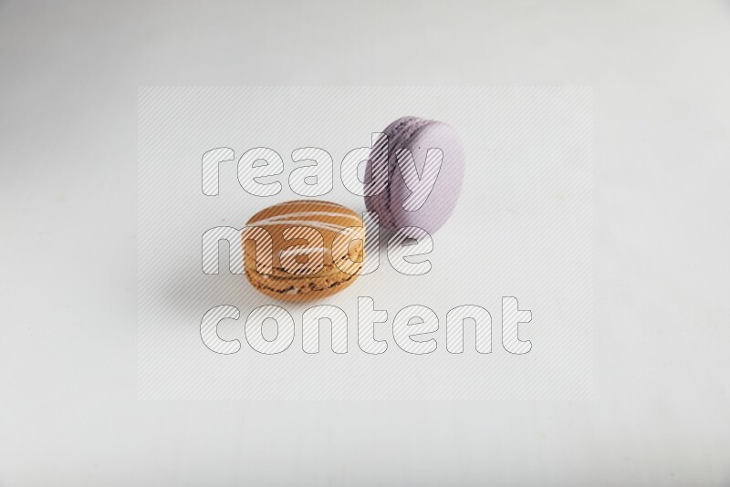 45º Shot of of two assorted Brown Irish Cream, and Purple Blueberry macarons on white background