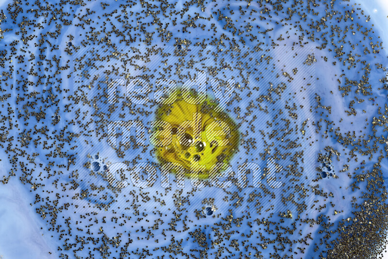 A close-up of sparkling gold glitter scattered on swirling blue and green background