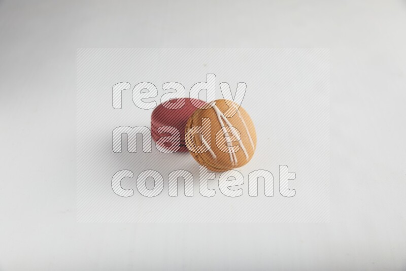 45º Shot of of two assorted Brown Irish Cream, and Red Velvet macarons on white background