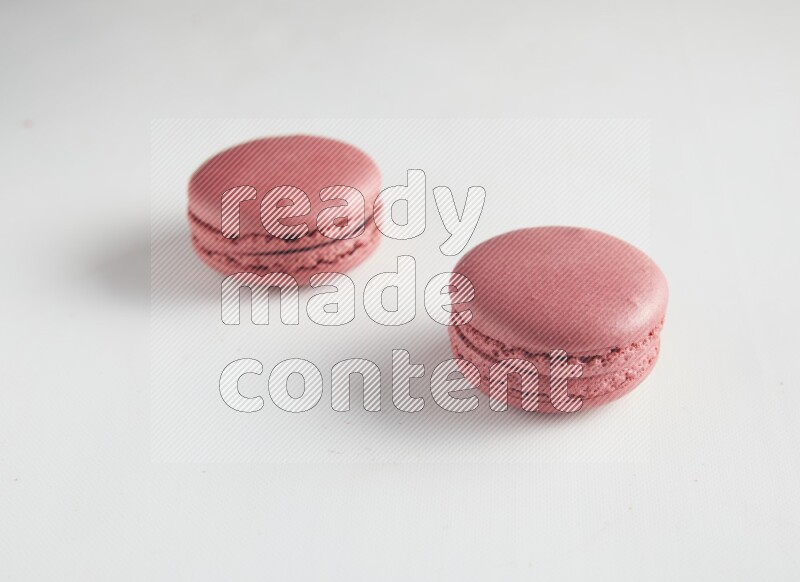 45º Shot of two Pink Raspberry macarons on white background