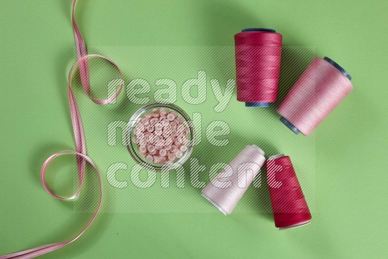 Pink sewing supplies on green background