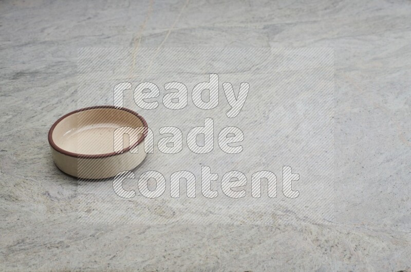 A beige pottery oven bowl on grey marble background