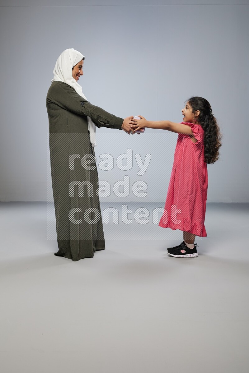 A girl giving a gift to her mother on gray background