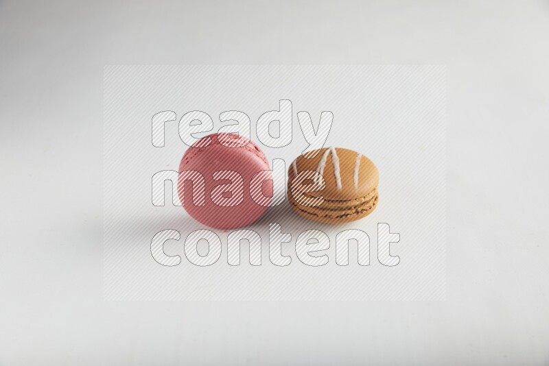 45º Shot of of two assorted Brown Irish Cream, and Pink Raspberry macarons on white background