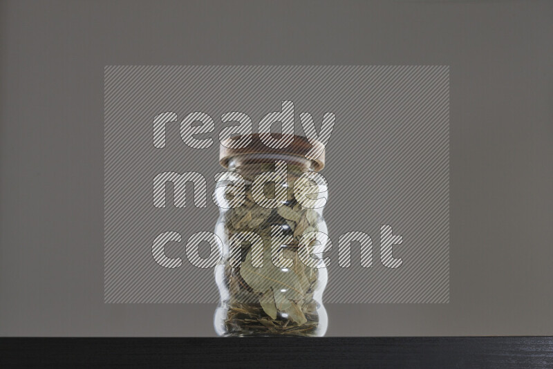 Bay laurel leaves in a glass jar on black background