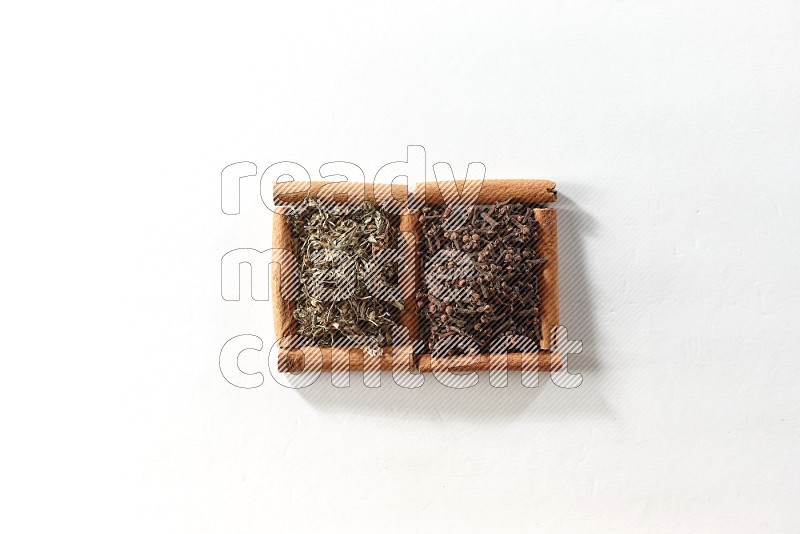 2 squares of cinnamon sticks full of cloves and dried basil on white flooring