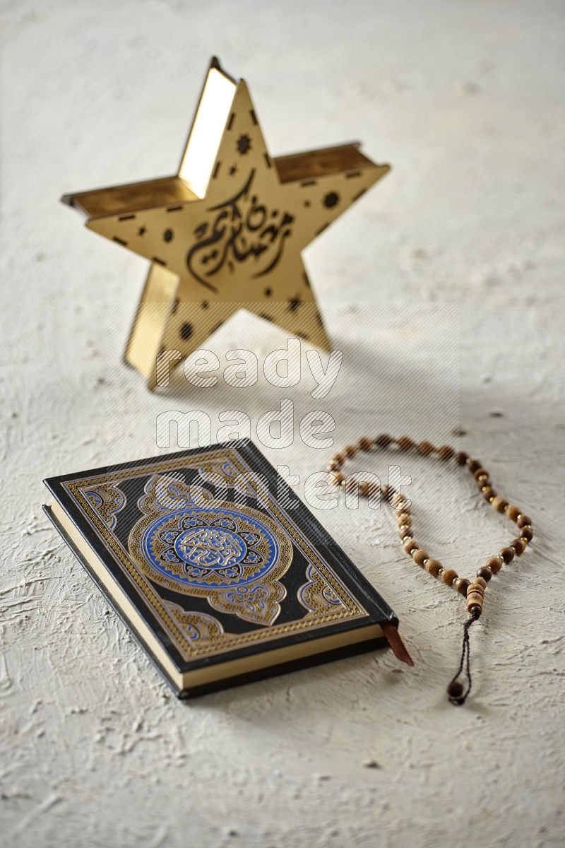 A wooden golden star lantern with different drinks, dates, nuts, prayer beads and quran on textured white background
