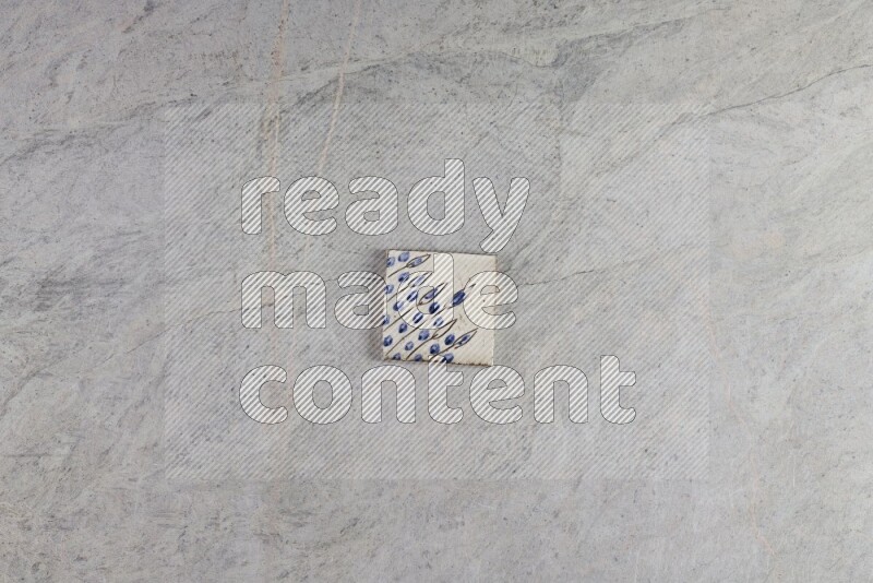 A decorative pottery coaster on grey marble background