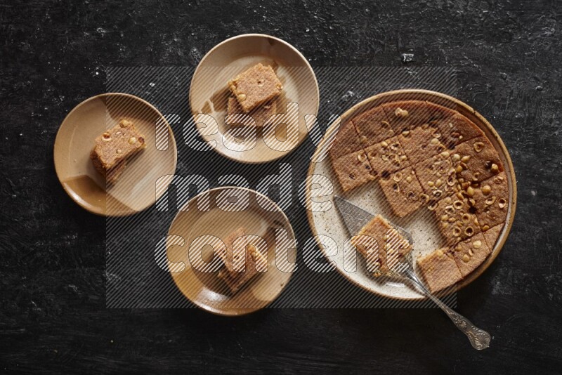 بسبوسة في أطباق مختلفه علي خلفية سوداء خشبية