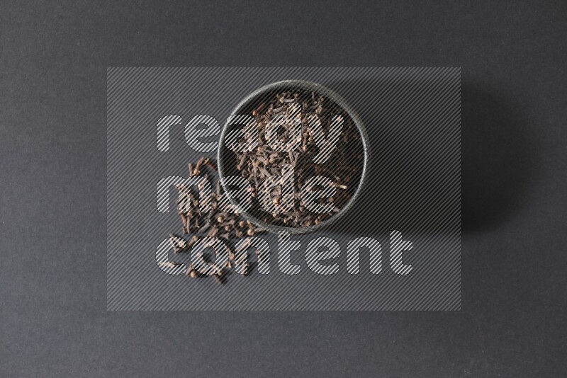 وعاء فخاري أسود ممتلئ بحبوب القرنفل علي خلفية سوداء