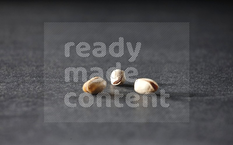 3 pistachios on a black background in different angles