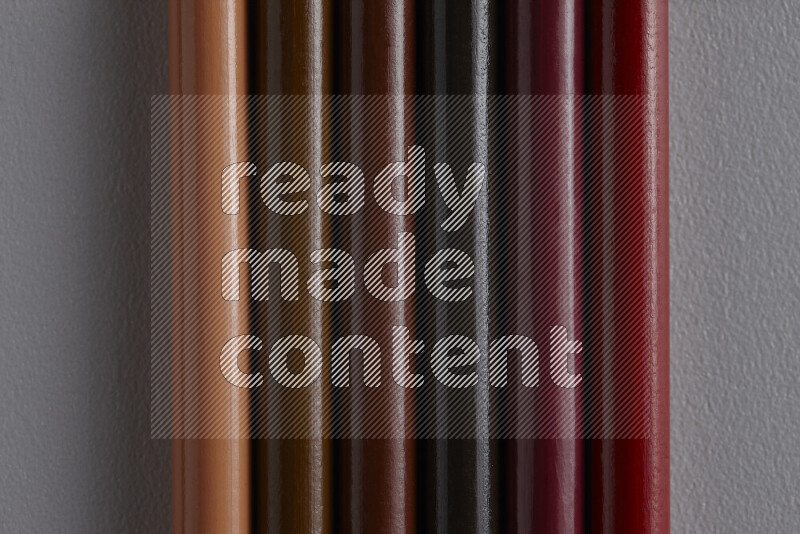 مجموعة من أقلام الرصاص الملونة مرتبة لتعرض تدرجا من الألوان البنية علي خلفية رمادية