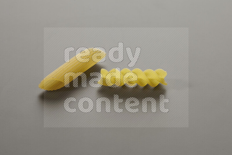 Penne pasta with other types of pasta on grey background