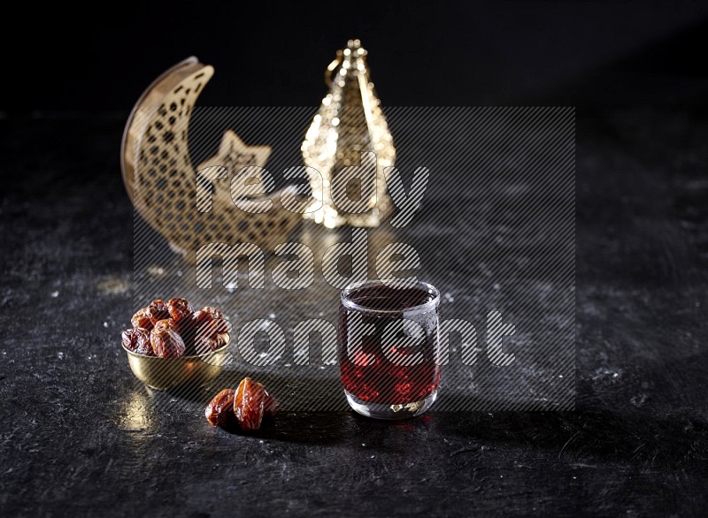 Dates in a metal bowl with Hibiscus beside golden lanterns in a dark setup