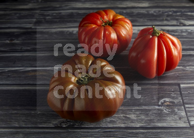 45 degree three heirloom tomato on a textured grey wooden background