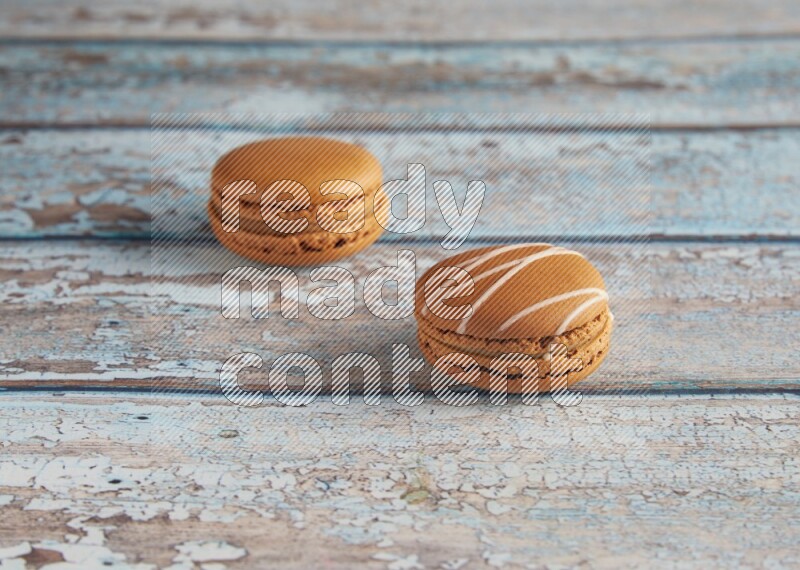 45º Shot of of two assorted Brown Irish Cream, and Brown Maple Taffy macarons  on light blue background