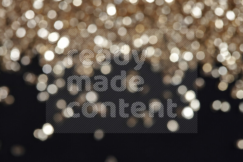 Gold shimmering fragments of glass scattered on a black background