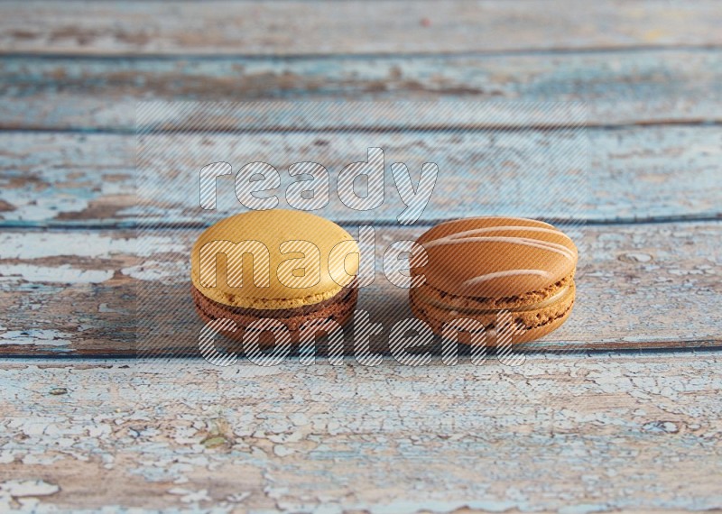 45º Shot of of two assorted Brown Irish Cream, and Yellow, and Brown Chai Latte macarons  on light blue background