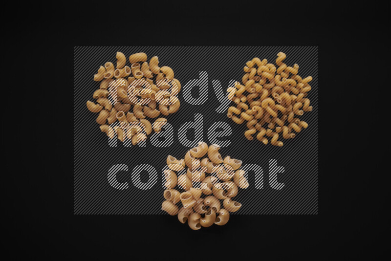 Different pasta types in bunches on black background