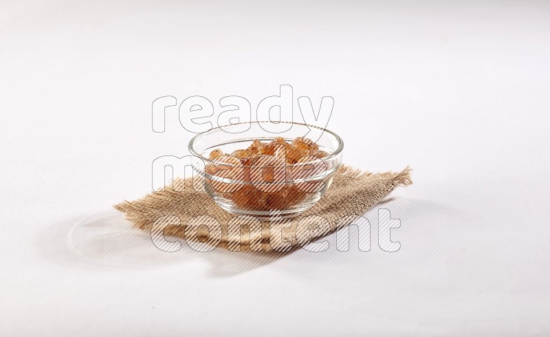 A glass bowl full of gum arabic on a burlap piece on white flooring in different angles