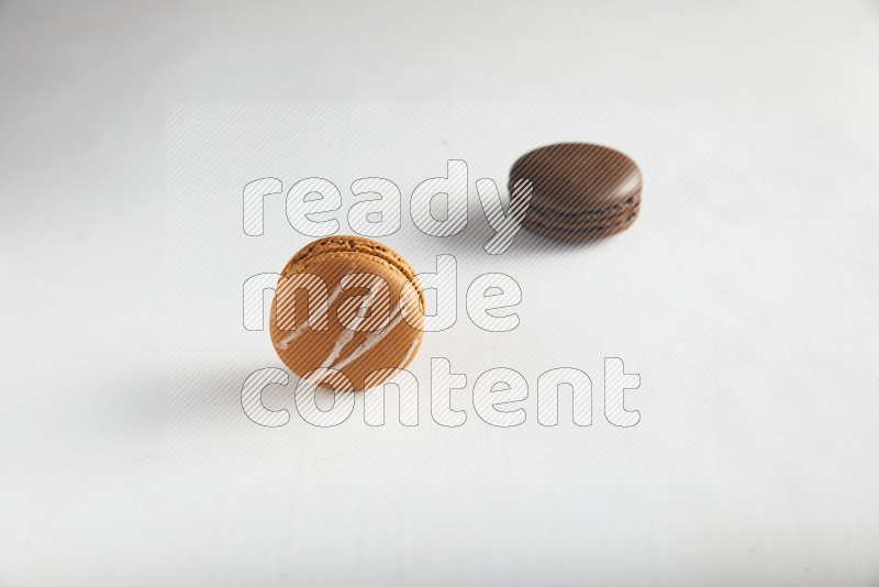 45º Shot of of two assorted Brown Irish Cream, and Brown Dark Chocolate macarons on white background