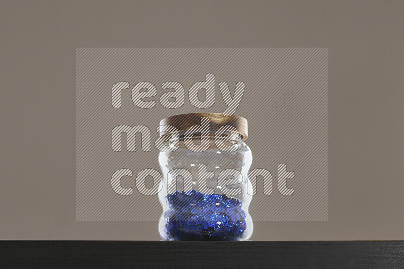 Sequins in a glass jar on black background