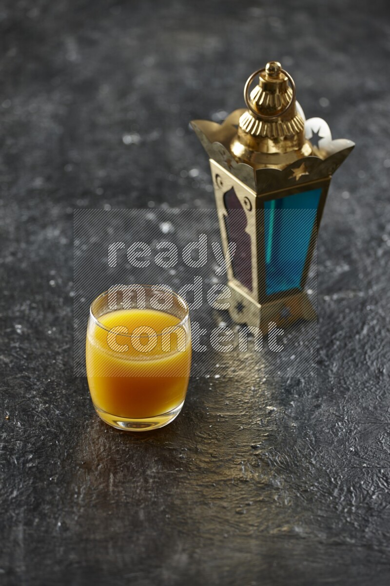 A golden lantern with different drinks, dates, nuts, prayer beads and quran on textured black background