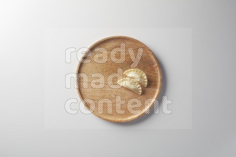 Two Sambosas on a wooden round plate on a white background